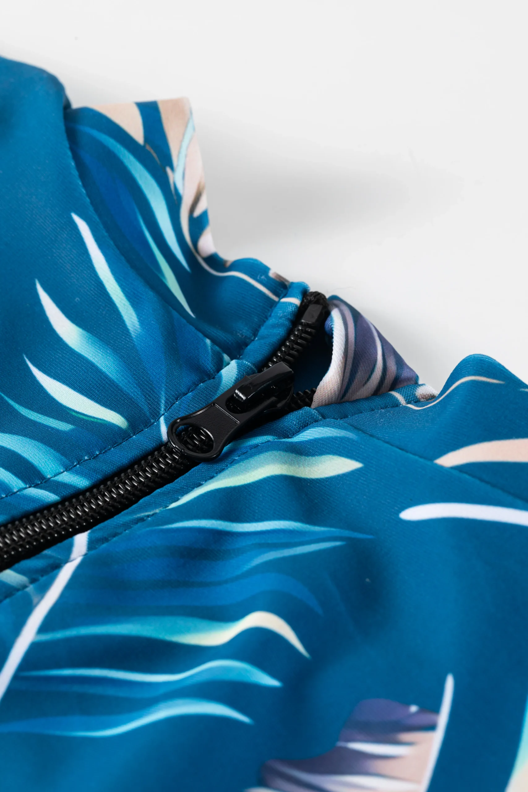 Back flat-lay of the teal tropical print short-sleeve onesie and matching solid teal swim shorts.